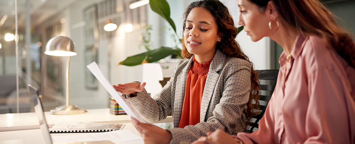 Two women discussing documents in office.