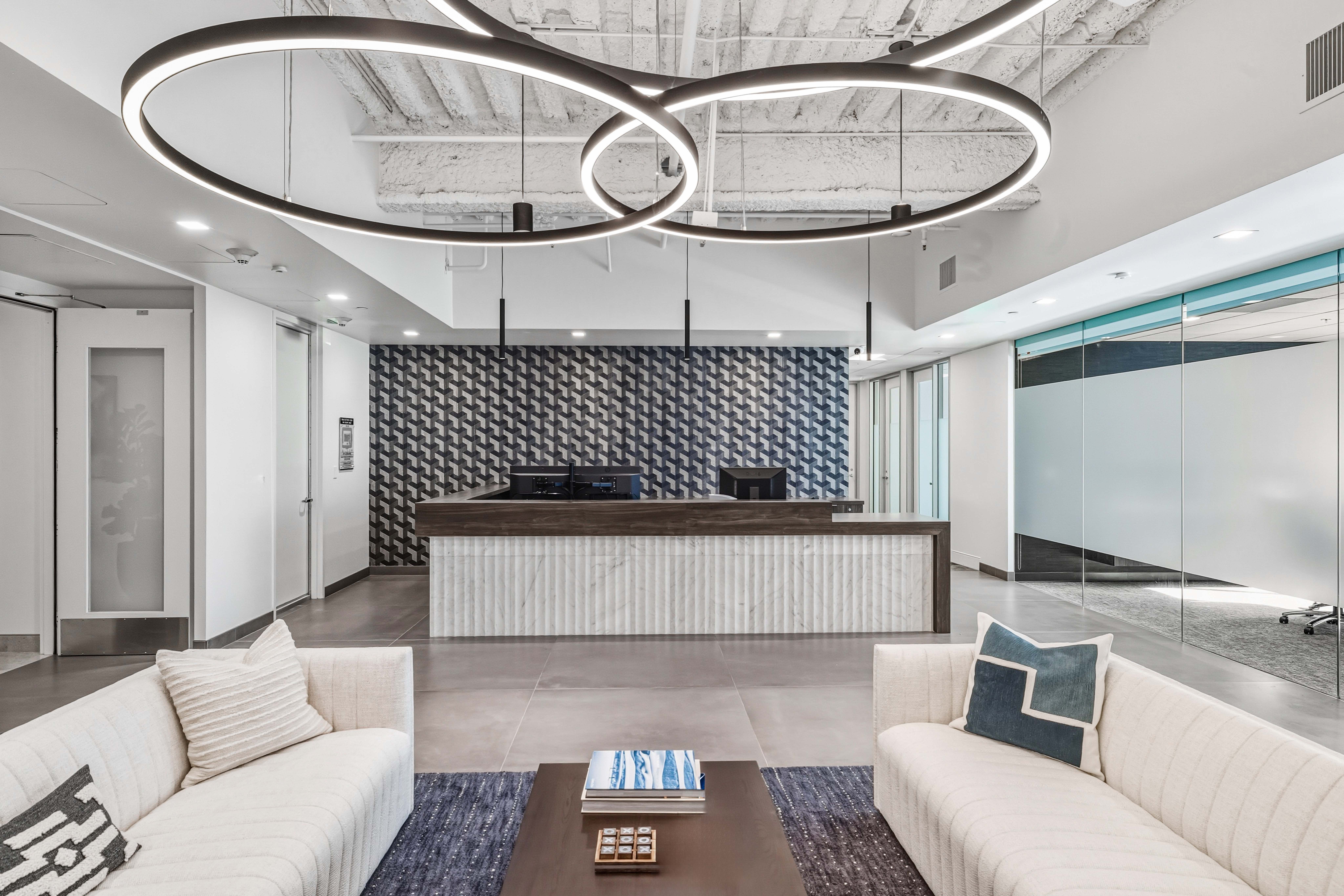 Modern reception area with exposed ceiling and white couches
