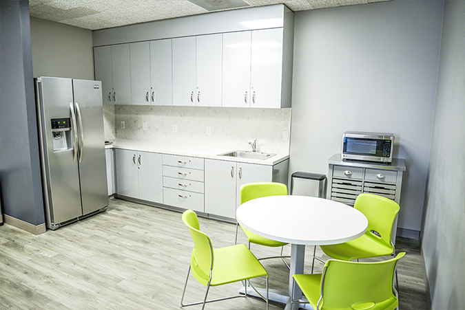 Modern kitchen with green chairs.