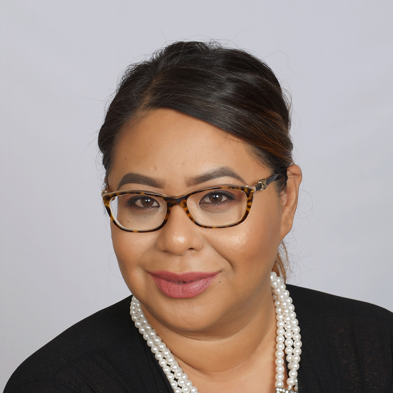 Woman with dark hair and jewelry.